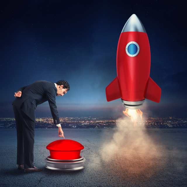 Businessman pressing launch button as red rocket takes off representing successful business launch and automated growth systems